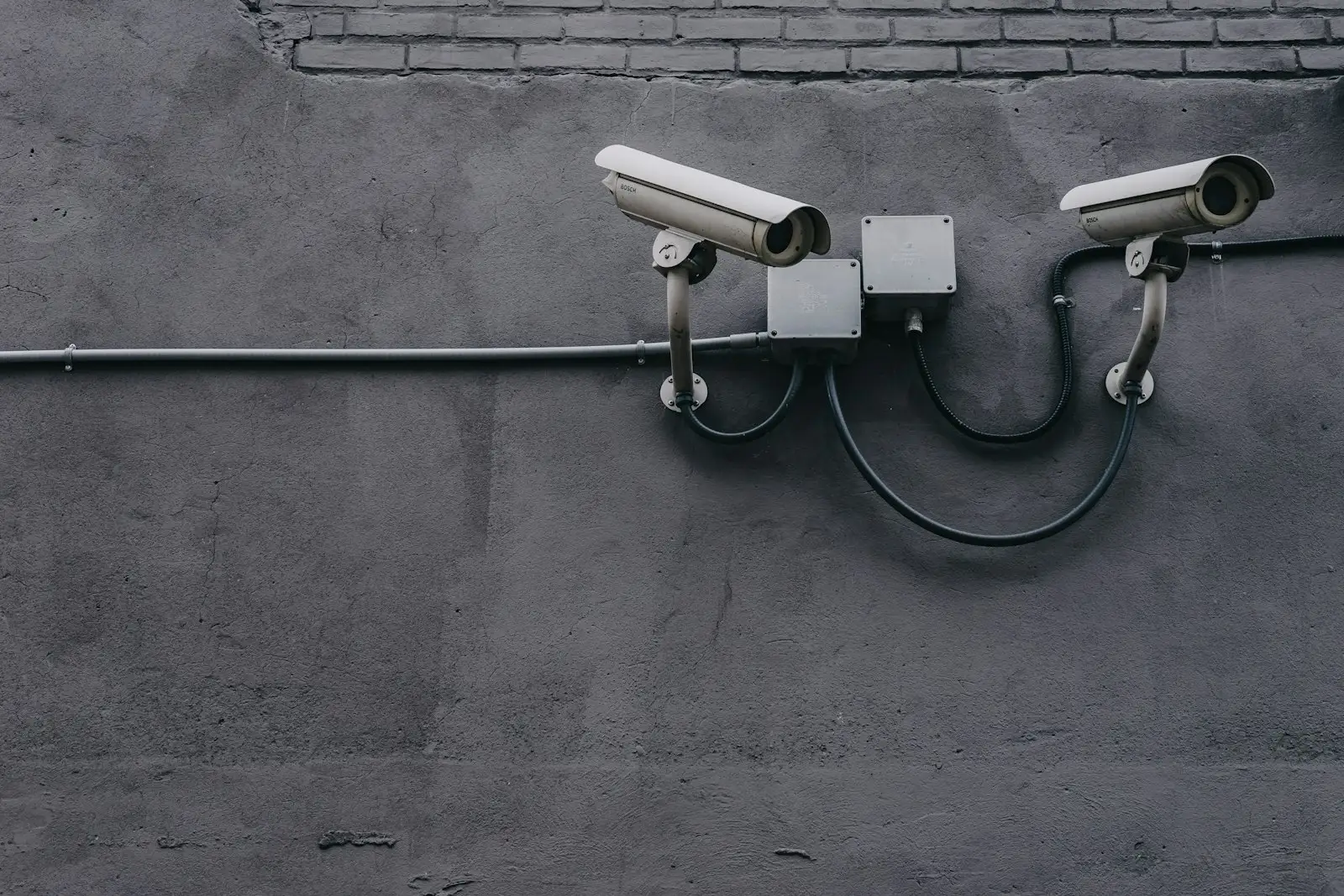 Two bullet security cameras mounted on a dark wall